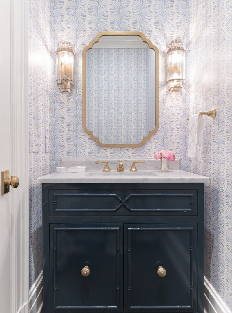 White marble bathroom sink styled with Sky Blue Botanical Stripe Custom Wallpaper with gold mirror hung in the center and two lamps by the side