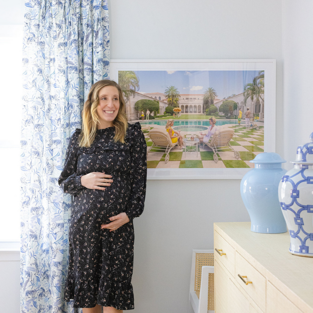 Blonde pregnant woman standing in front of blue tiger chinoiserie curtain panel and colorful artwork