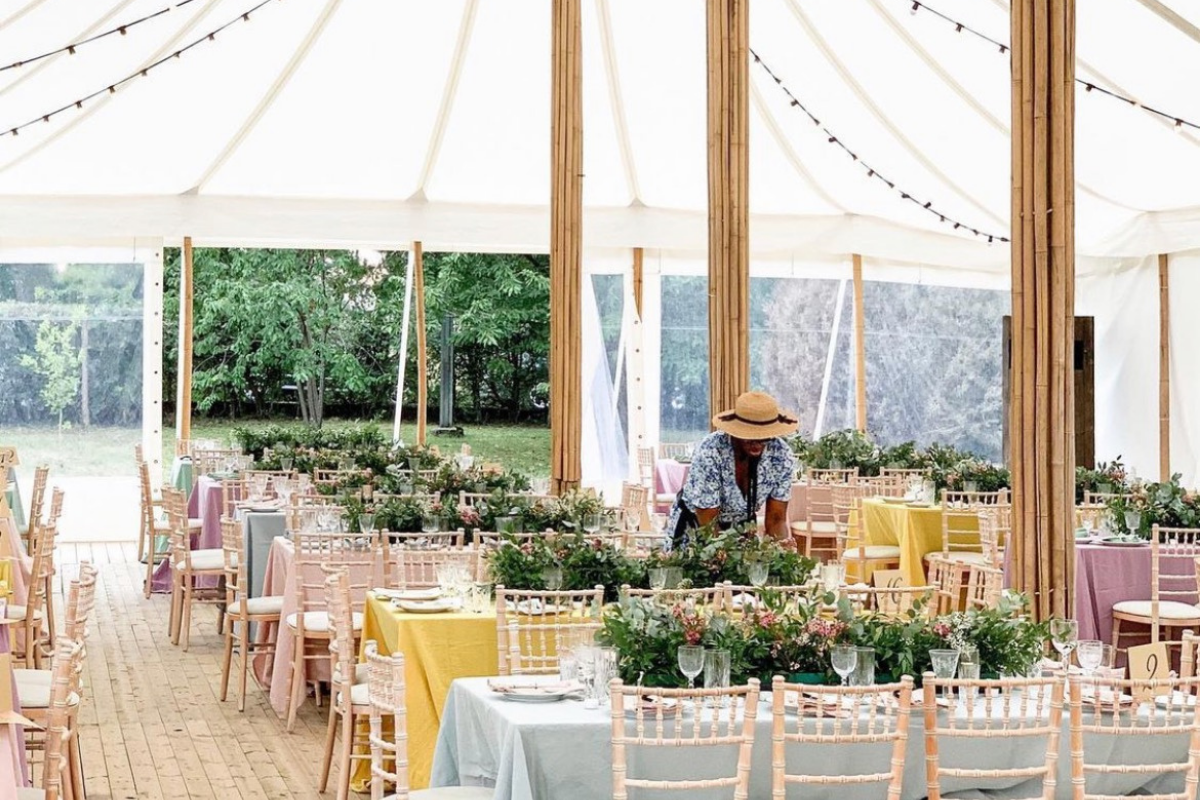 Outdoor venue with white rectangular tables and white chairs with stylish tablescapes
