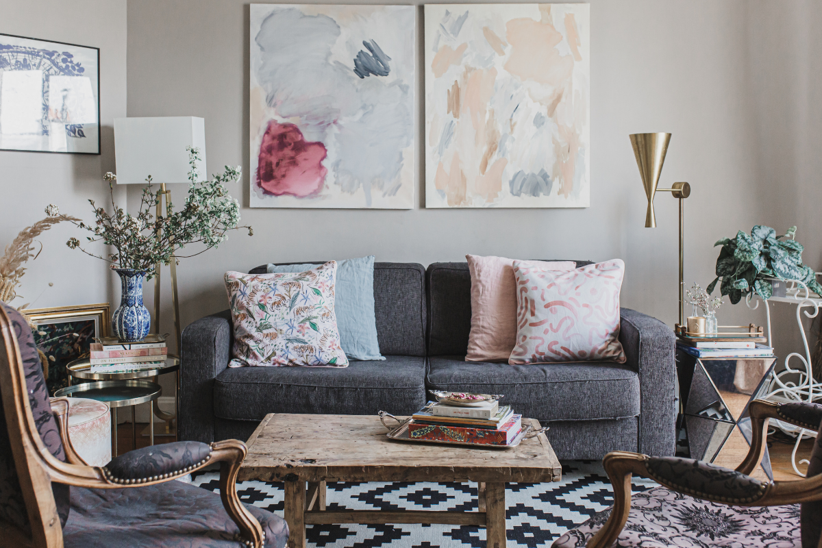 Grey couch in living room styled with a Pink Chinoiserie Tiger custom pillow, a green pillow, a pink pillow, and a Pink Graphic custom pillow in front of a coffee table and two antique chairs in the front