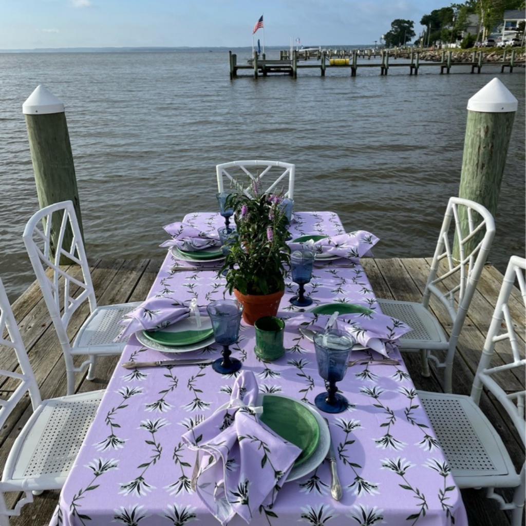 Lavender floral tablecloth styled with lavender floral napkins on a table on a dock along the water