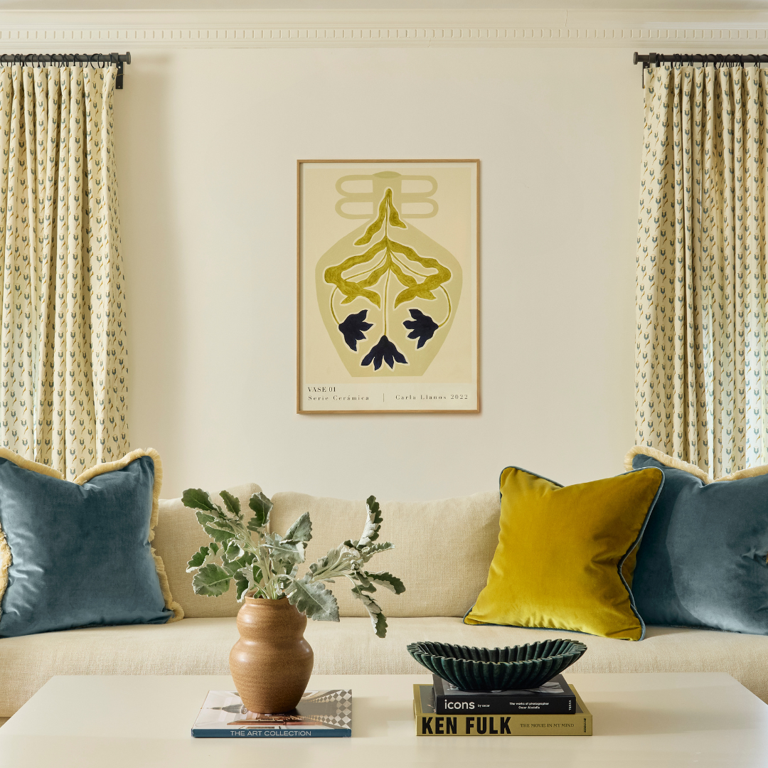 Living room with white walls and two blue and green floral curtain panels hanging on a black rod behind a white couch styled with peacock velvet pillows and a citron velvet pillow