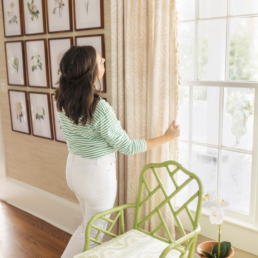 Brunette woman in front of window holding beige palm custom curtains