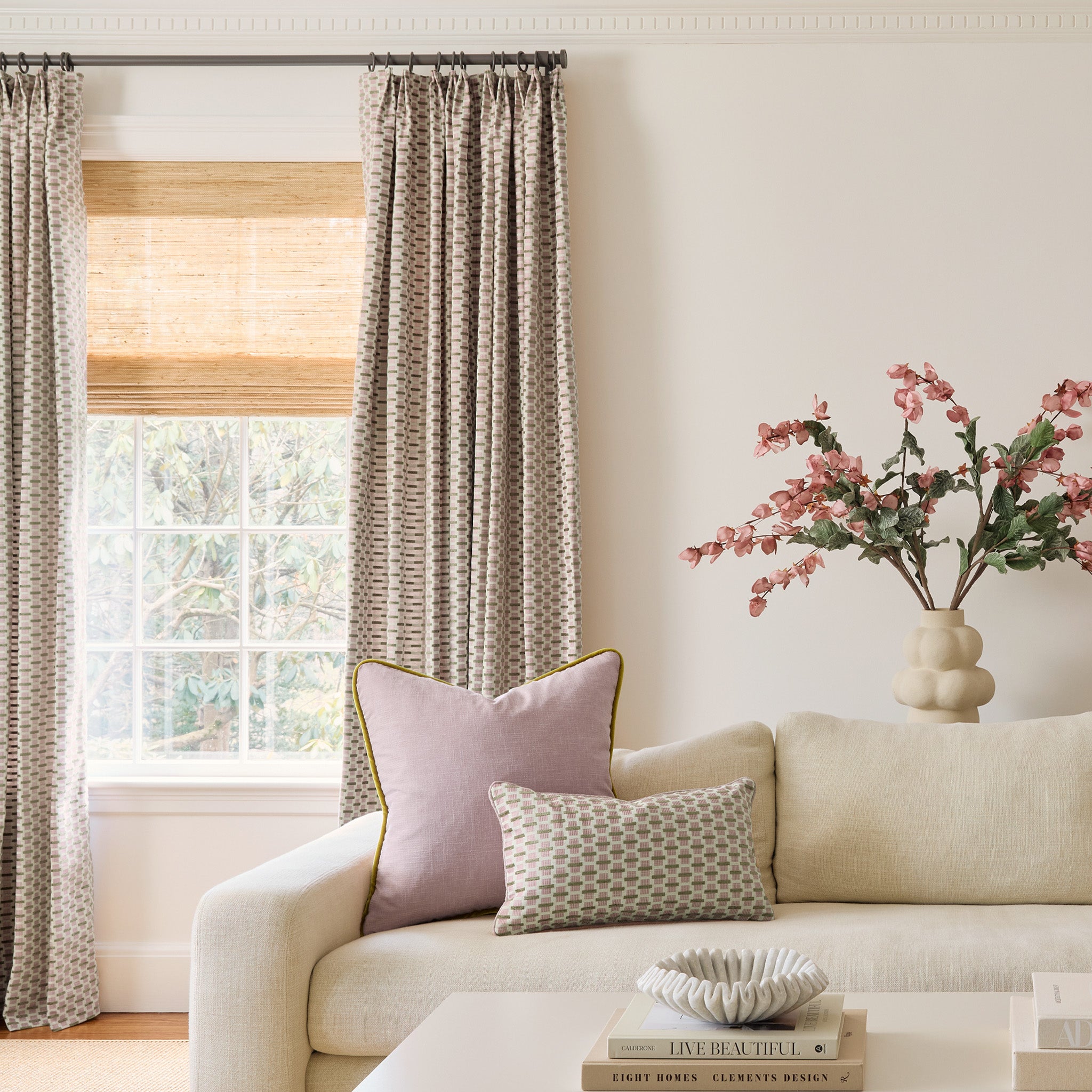 Living room with pink and citron chenille and woven jacquard curtains on a window behind a white couch with a light pink pillow and a coordinated pink and citron chenille and woven jacquard pillow
