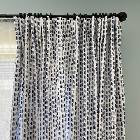 Close-up of Sky and Navy Blue Poppy Custom Curtain on black rod in front of window