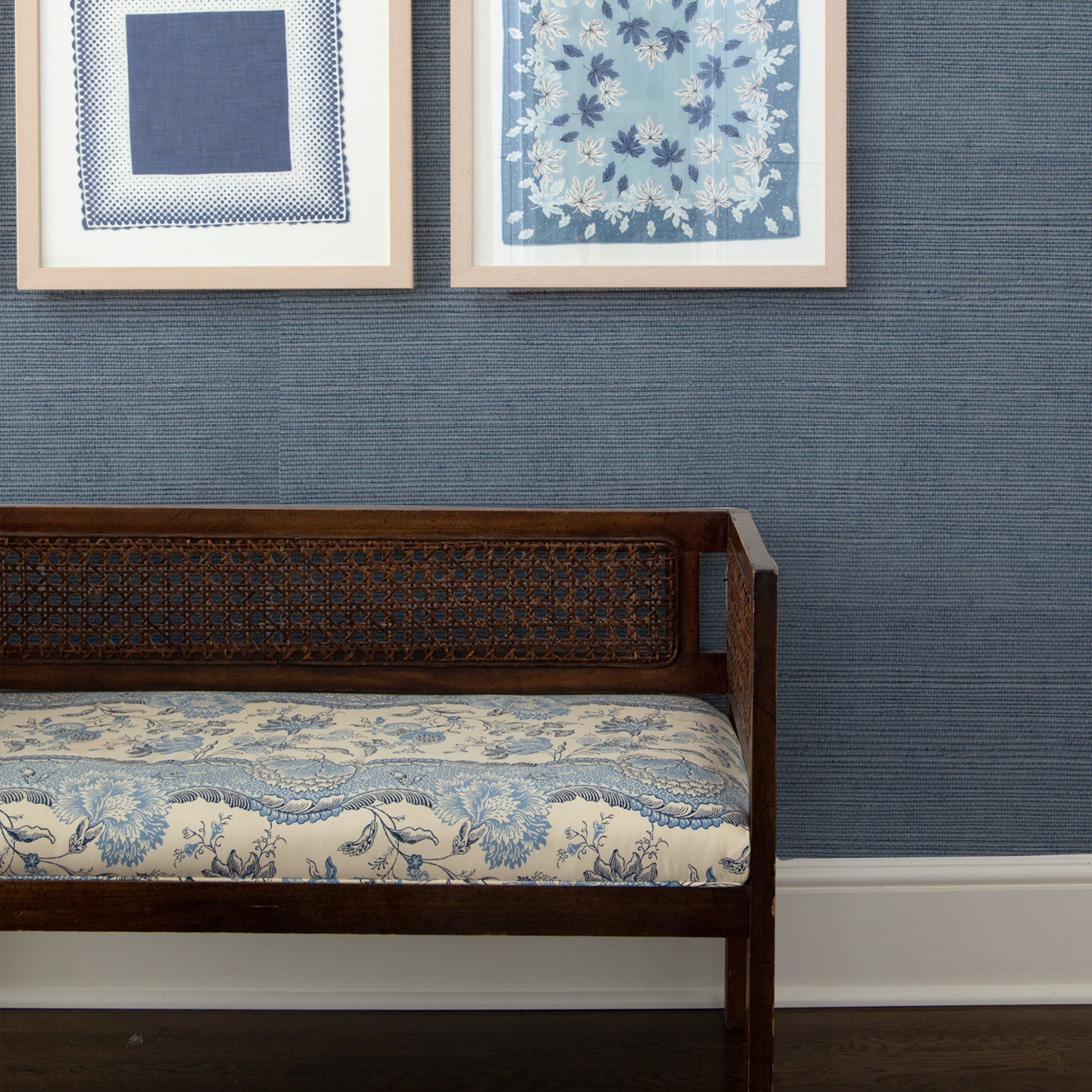 Navy blue solid grasscloth on a wall behind a wooden bench with blue and white patterned cushion styled with blue artwork