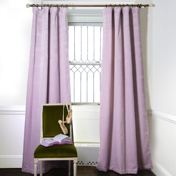 Lilac Velvet Custom Curtains on metal rod in front of an illuminated window with a Moss Green Velvet chair with a pair of ballerina shoes hanging and an open book on top