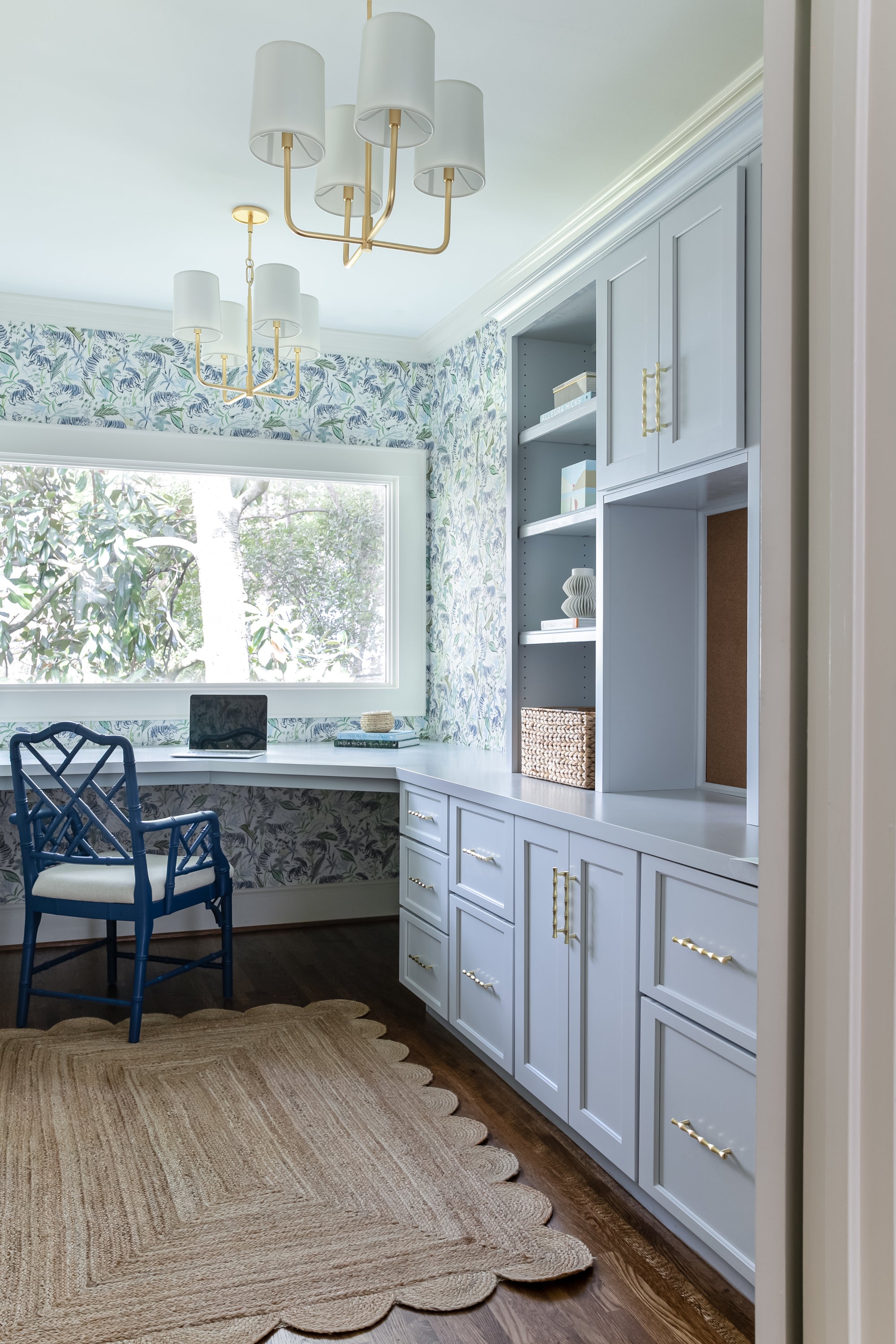 Office with green tiger chinoiserie wallpaper and light blue painted cabinets and shelves with a large picture window looking outside