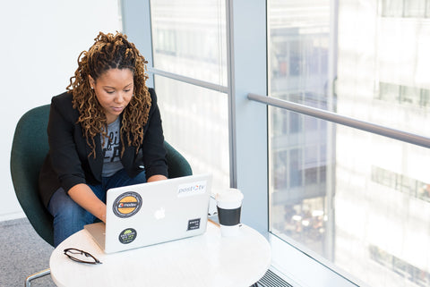 Black woman with locs looks at computer in business setting