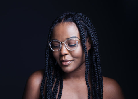 Black woman with box braids and glasses against Black backdrop