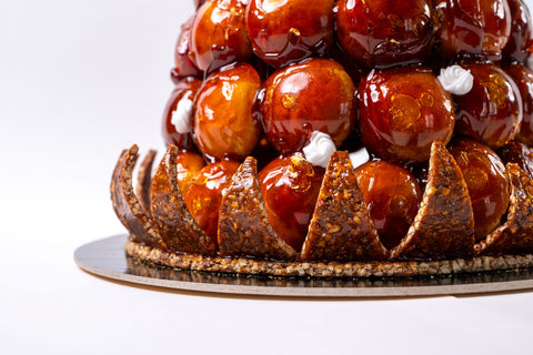 Croquembouche, also known as "pièce montée," is a traditional French dessert with a rich history, made for special occasions & celebrations! The term "croquembouche" is derived from the French words "croquant" (which means crunchy) and "bouche" (which means mouth), referring to the dessert's characteristic crunchy texture.  These towers of cream-filled choux date back to the 18th century and in France one always gets excited to be invited to such special event as it is not a dessert that can be found ready to go in pastry shops.  A pièce montée definitely makes get togethers memorable for everyone!