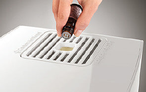 Close-up of top of Boneco S250 humidifier showing a hand pouring essential oil in to add a scent