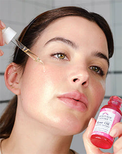 woman applying Rose Oil to face