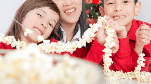 Children stringing popcorn with parents