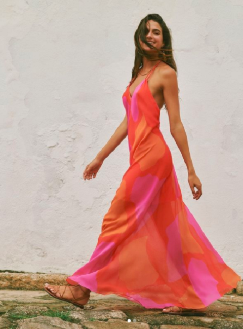 Model wearing brightly colored, low back, light maxi dress