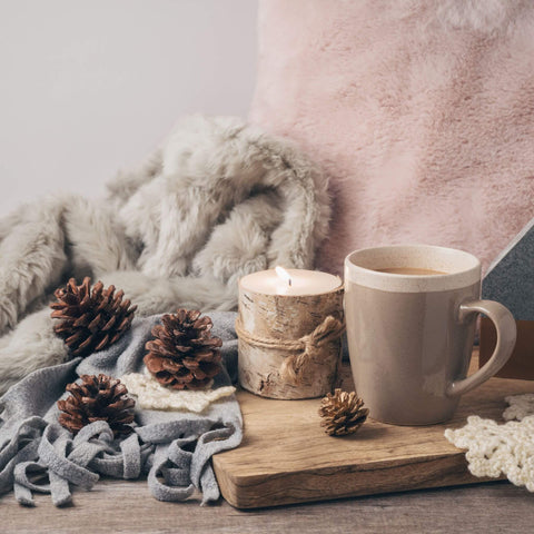 Image of hygge with fuzzy blankets, warm tea, a book and candle