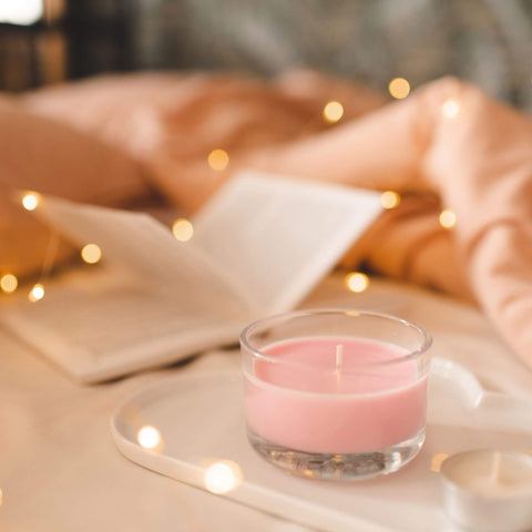 Image of hygge with candle, twinkle lights, pink fuzzy blanket and a book