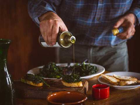 Man pouring extra vigin olive oil on vegetables