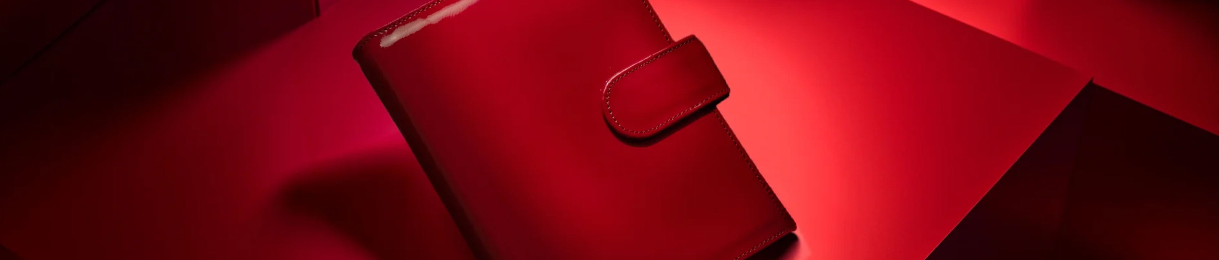 Detailauschnitt eines Bildes von einem roten Lackleder-Ringbuch in roter Umgebung.