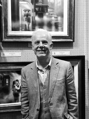 Artist Tim Shorten standing in front of a display of his original paintings and prints at The Acorn Gallery, Pocklington near York.