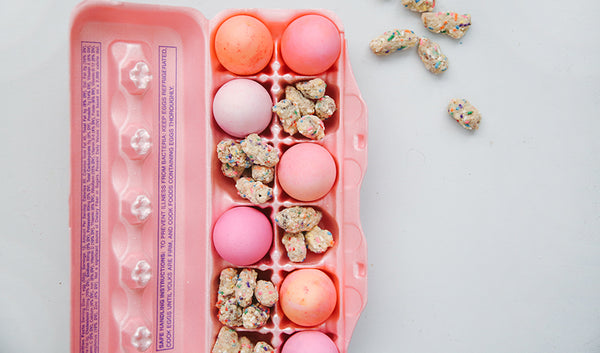 Pastel colored Easter eggs and chocolate covered pretzel bites in an egg carton