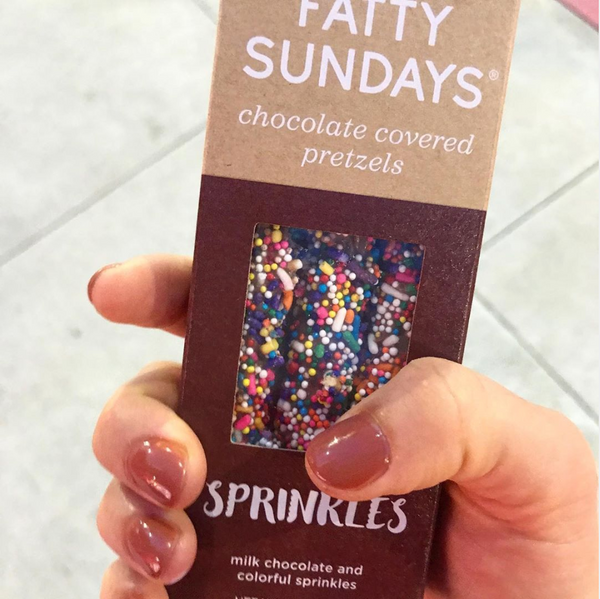 Rainbow sprinkles milk chocolate covered pretzels in a brown box with a brown background
