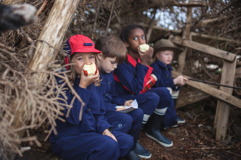 Kids who attend the forrest school during snack time in the forrest.