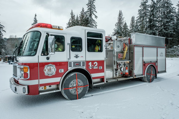 Canadian firefighter truck with mounted AutoSock on front and rear wheels, standing on snow in nature