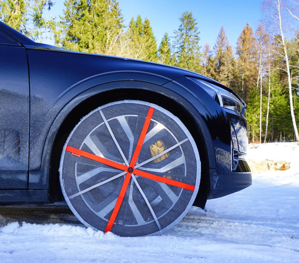 AutoSock mounted on front wheels of a passenger car, standing on snow in winter nature
