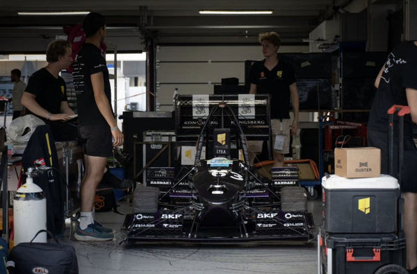 Lyra racing car of Revolve NTNU with AutoSock tire covers mounted, standing in paddock