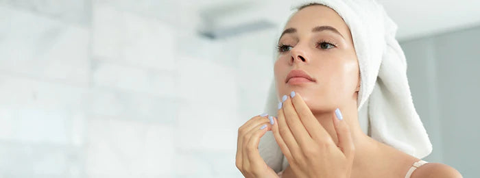 A woman is touching her face by looking at the mirror