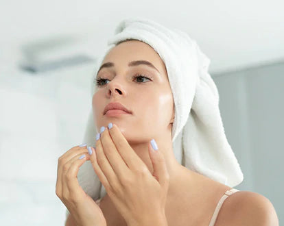 A woman is touching her face by looking at the mirror