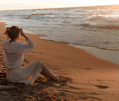 A woman is enjoying the view by sitting on the beach