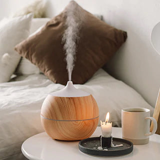 An aroma diffuser along with candle & coffee mug on the table in the room