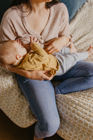 mom breastfeeding baby on bed