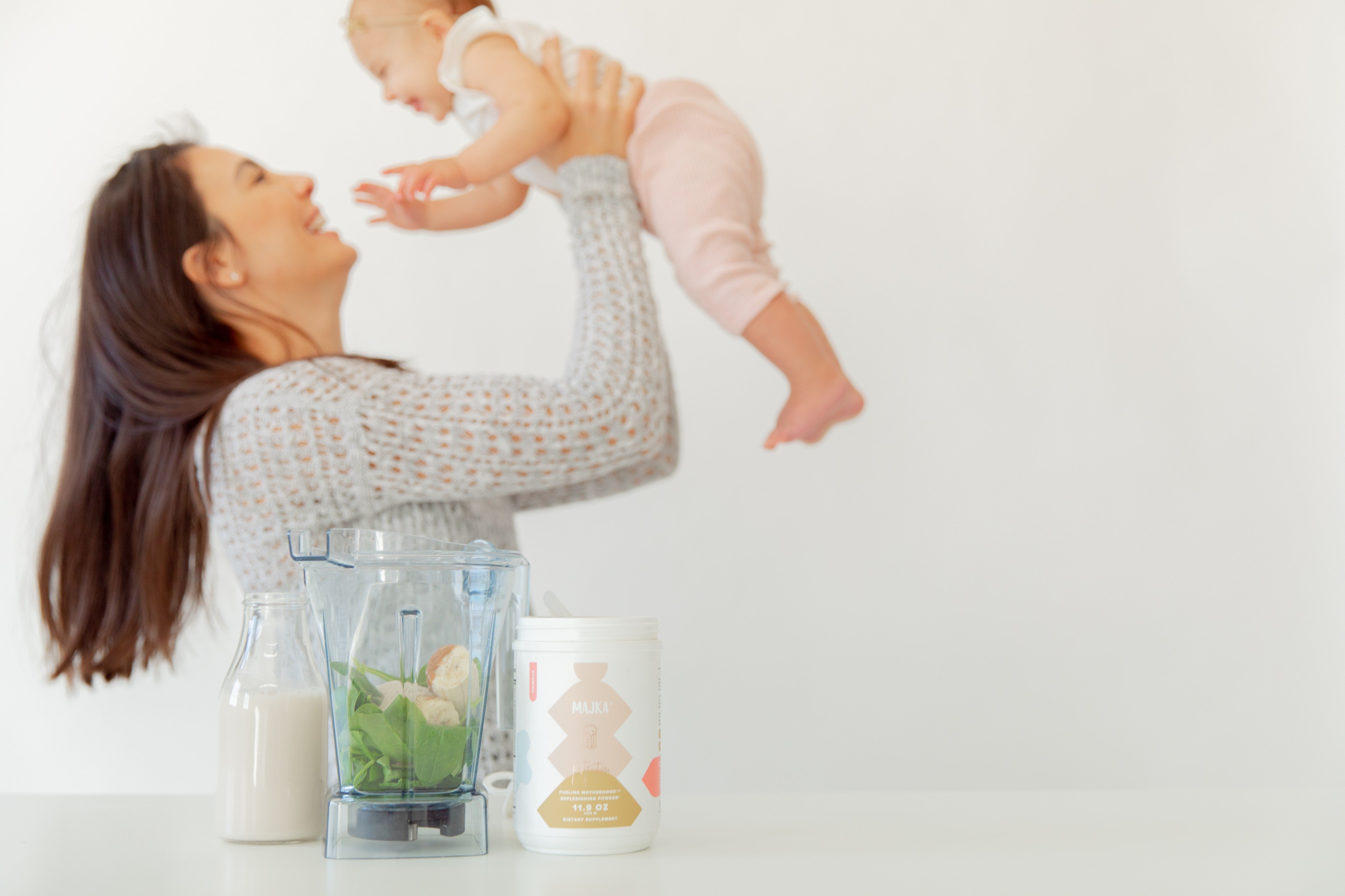 Mom holding baby while making smoothie