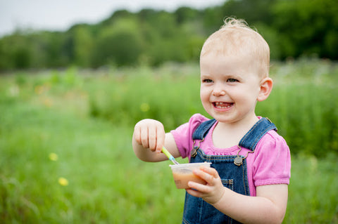 Baby girl eating biodynamic baby food on the farm