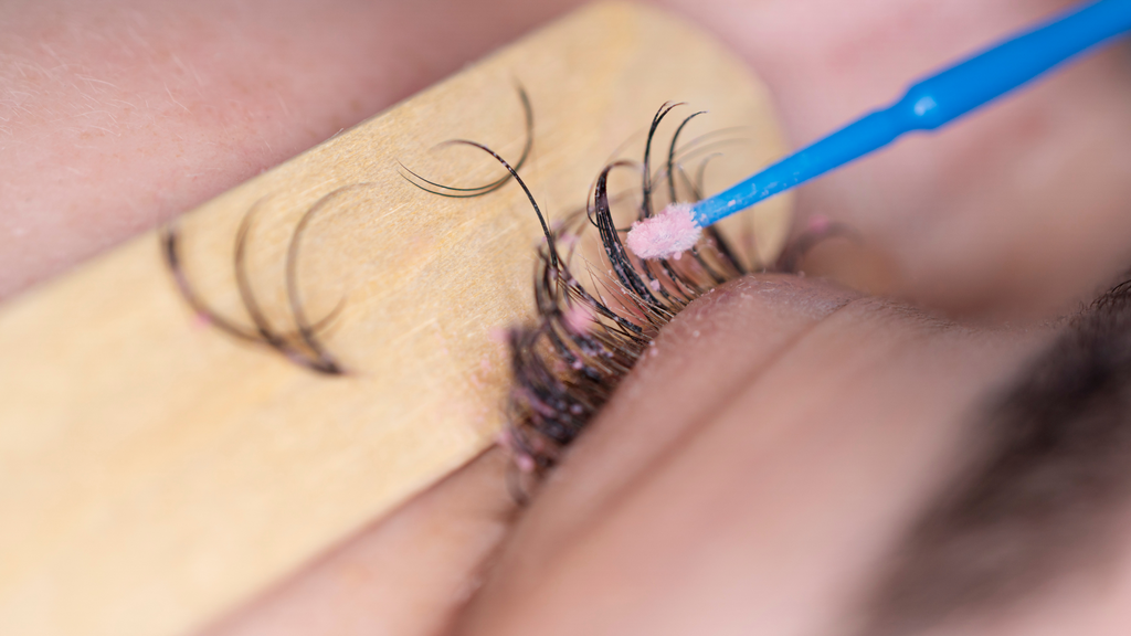 Close-up of a lash tech carefully removing eyelash extensions with tools.