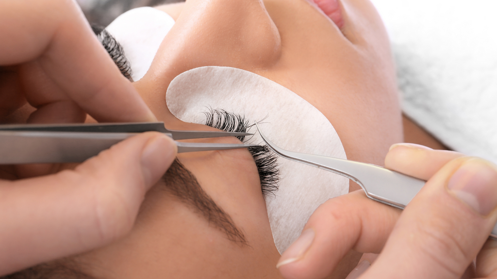 Close-up of a lash tech removing eyelash extensions.