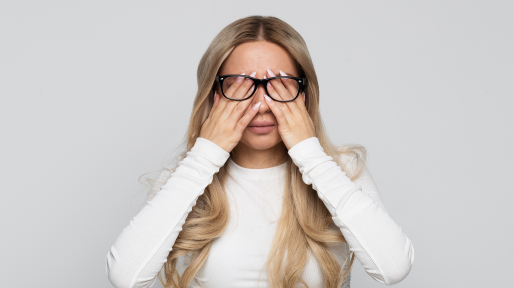 Woman wearing glasses and rubbing her eyes