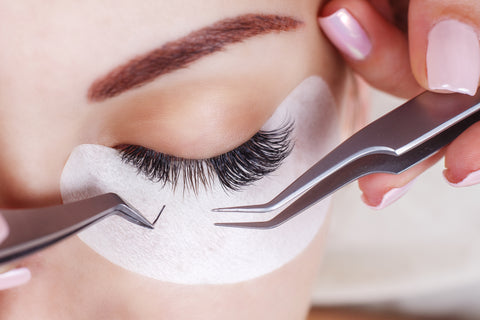 A lab technician applies hybrid lash extensions to the eyes of a customer. 