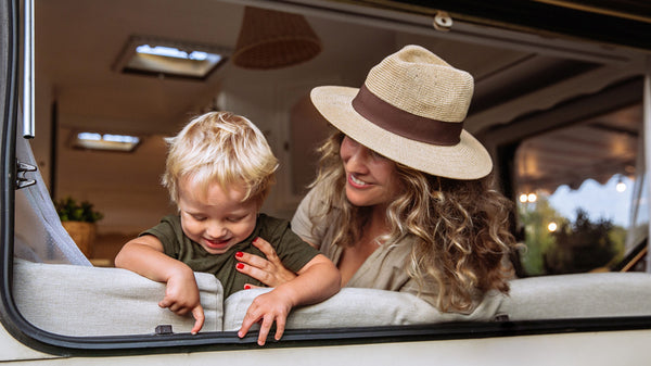 Woman and smiling baby in camper window playing