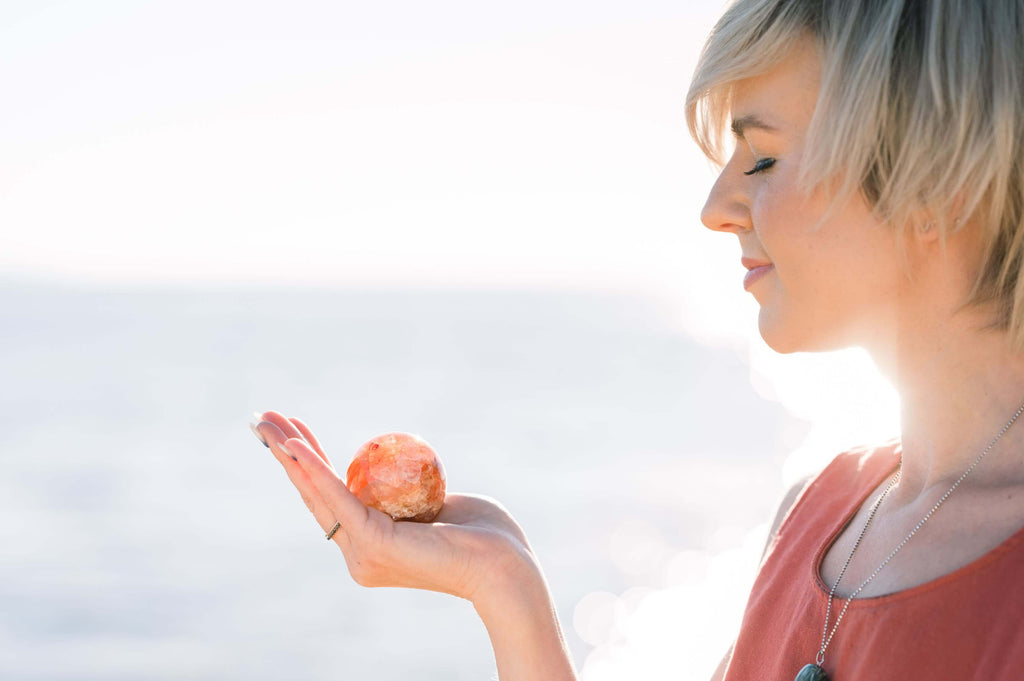 woman holding a crystal in her hand at the beach. are bigger crystals better?