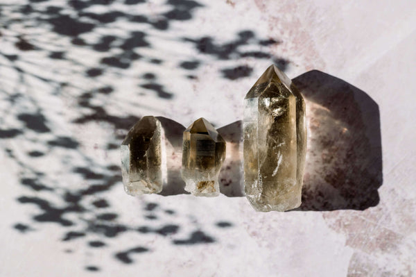 Set of 3 smoky quartz points with an artistic shadowy background