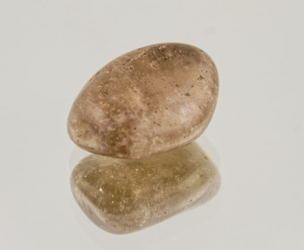 Smoky quartz tumble on a mirror with its reflection