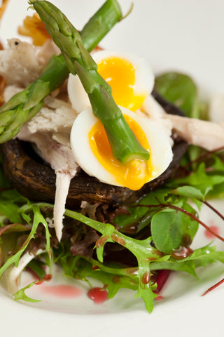 Warm salad of smoked, corn fed, local chicken with asparagus and quails eggs on a field mushroom