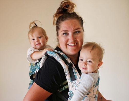 woman wearing twins - one in a tula on her front one in a tula on her back tandem wearing