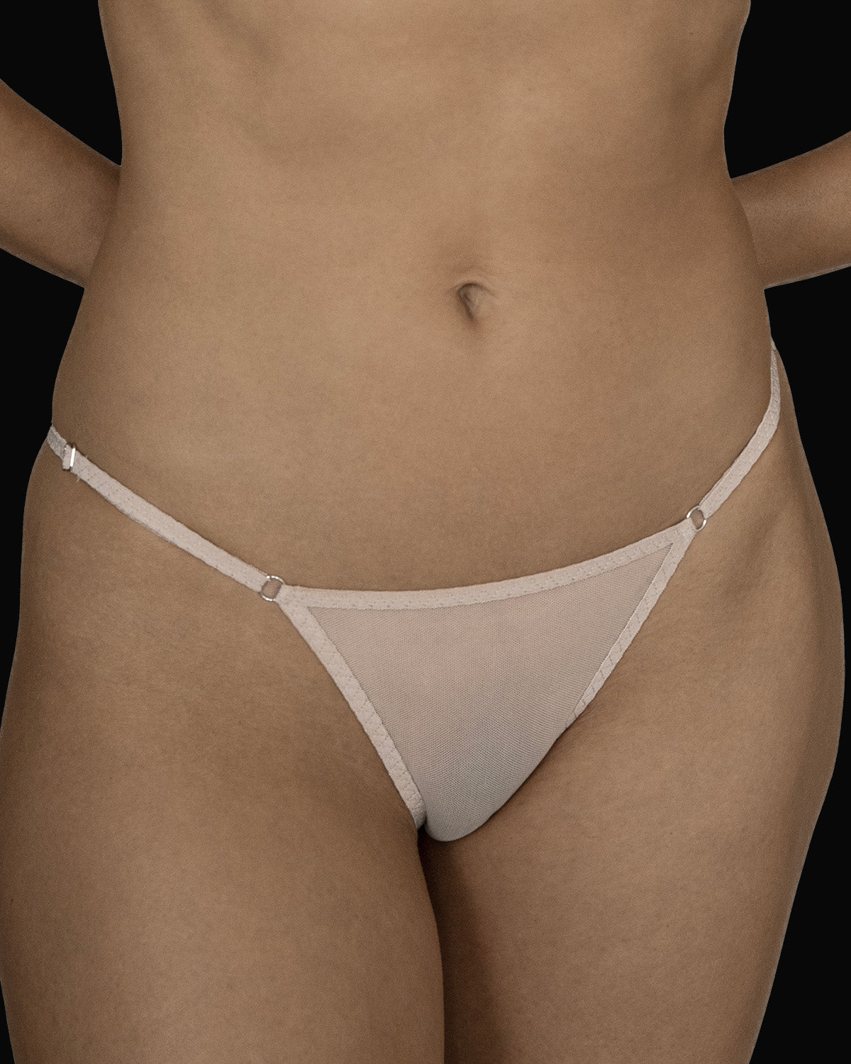 The Kye Intimates Essential String Bikini in the color ecru. A sheer pair of underwear that offers minimal front and back coverage. These delicate briefs have adjustable sliders on the waistband for ease of wear.