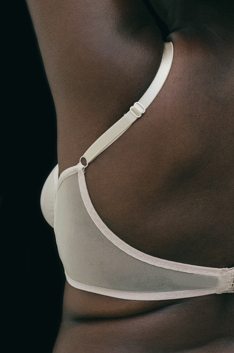 A view of the back of the Kye Intimates Form Bra in the color ecru. This bra offers the perfect balance between structure and comfort. This sheer bra is wire free, with adjustable shoulder straps and an adjustable back clasp. This wire free v neck bra provides moderate support, and is comfortable yet feminine.