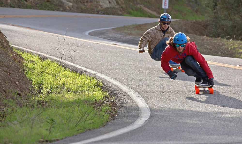 Couple of guys going downhill and thinking about what's the best longboard wheel. 